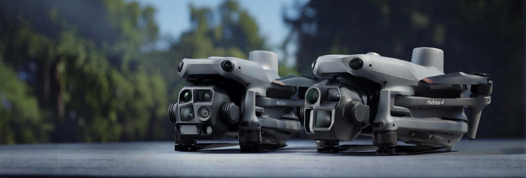Two Matrice 4 Series drones on a surface with a blurred natural background
