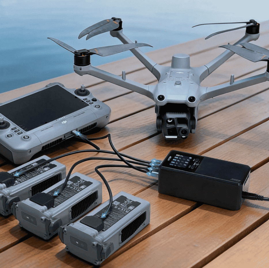 LKTOP 300W charging hub connected to three battery charging cradles beside a DJI Matrice drone and remote controller outdoors
